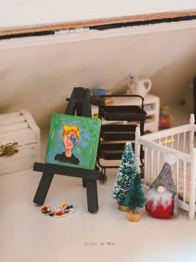 Miniature painting on easel with toys and christmas decorations around it