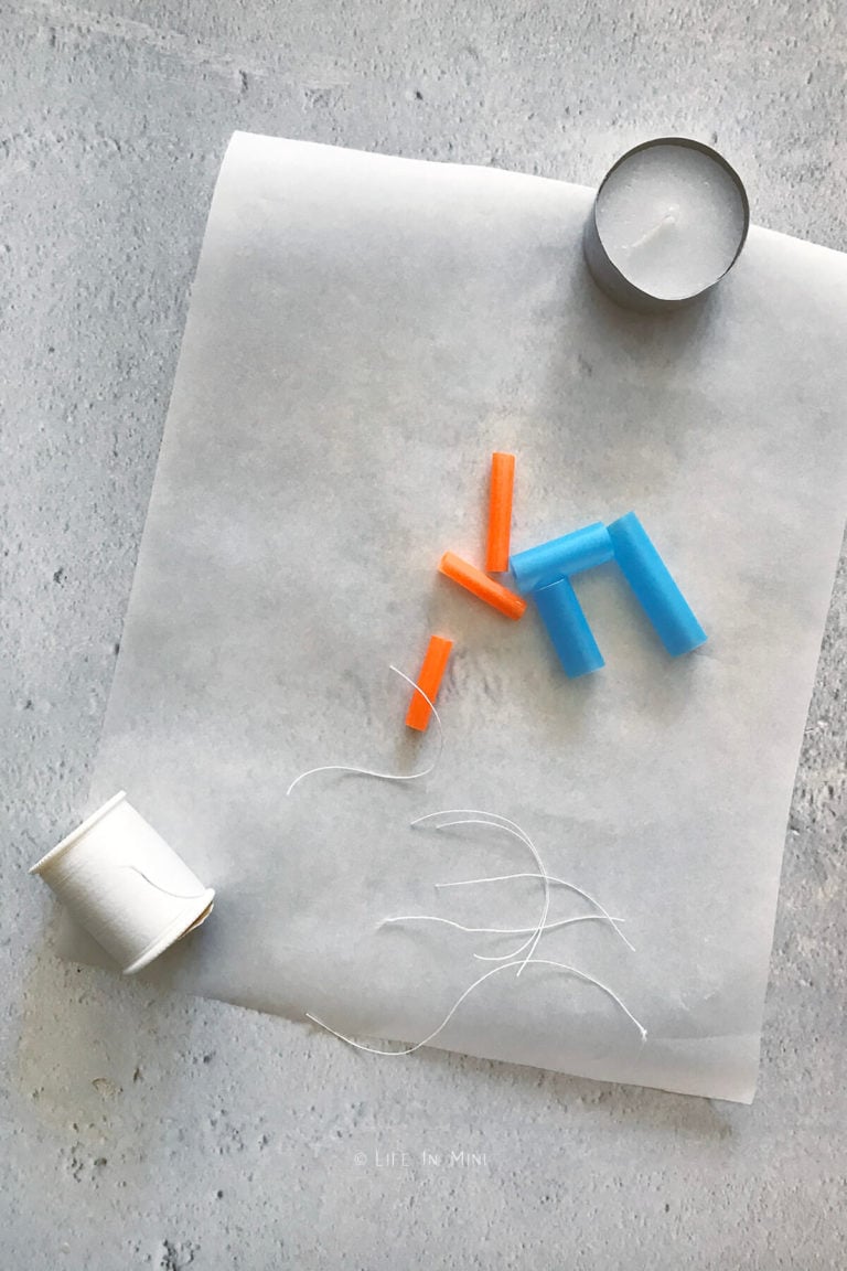 Cut up straws with some thread on parchment paper with a tea light next to it