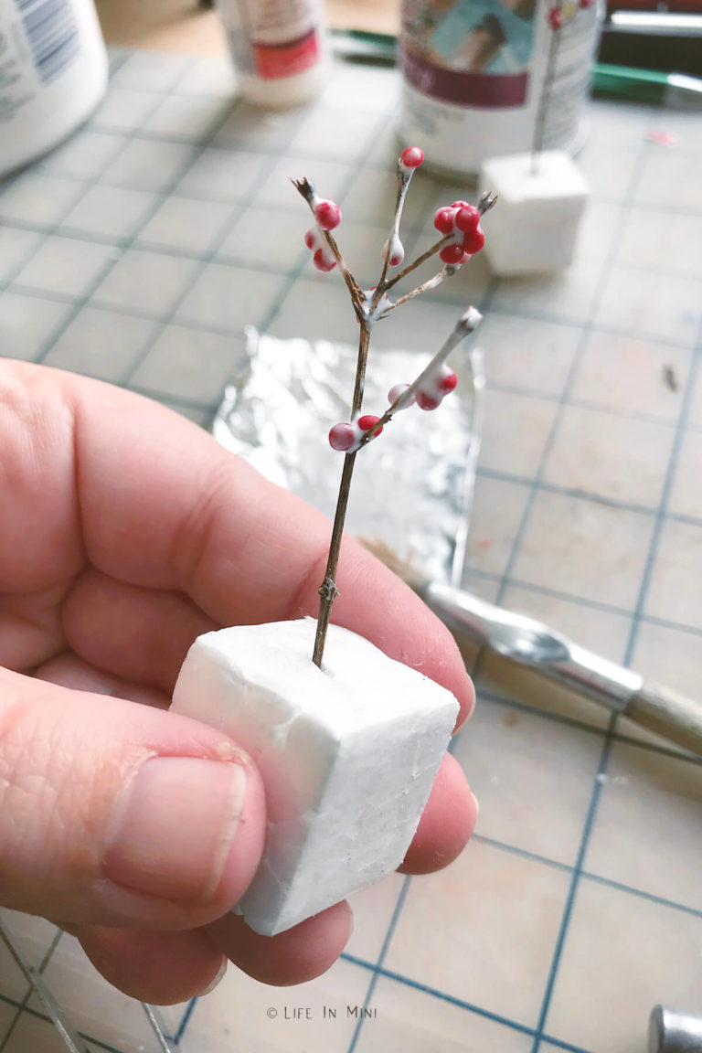 Using glue to adhere clay red berries onto twigs and glazed with watered down glue