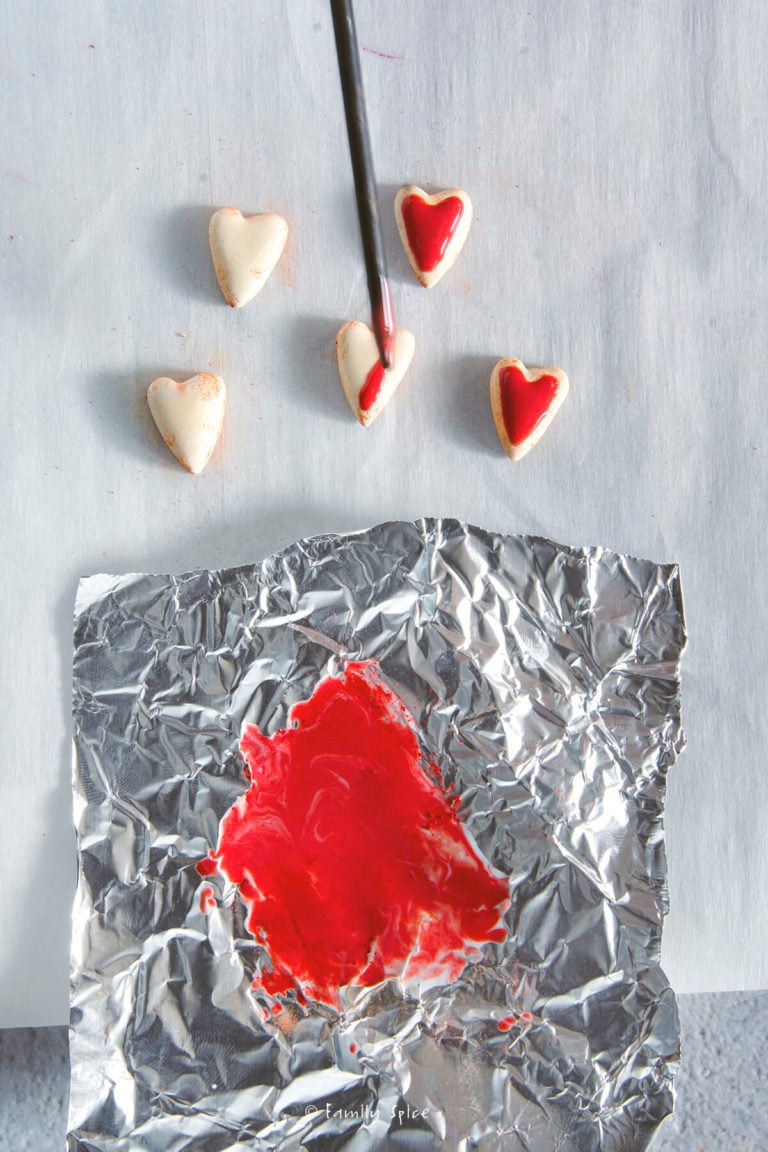 Using red liquid polymer to ice the miniature heart cookies