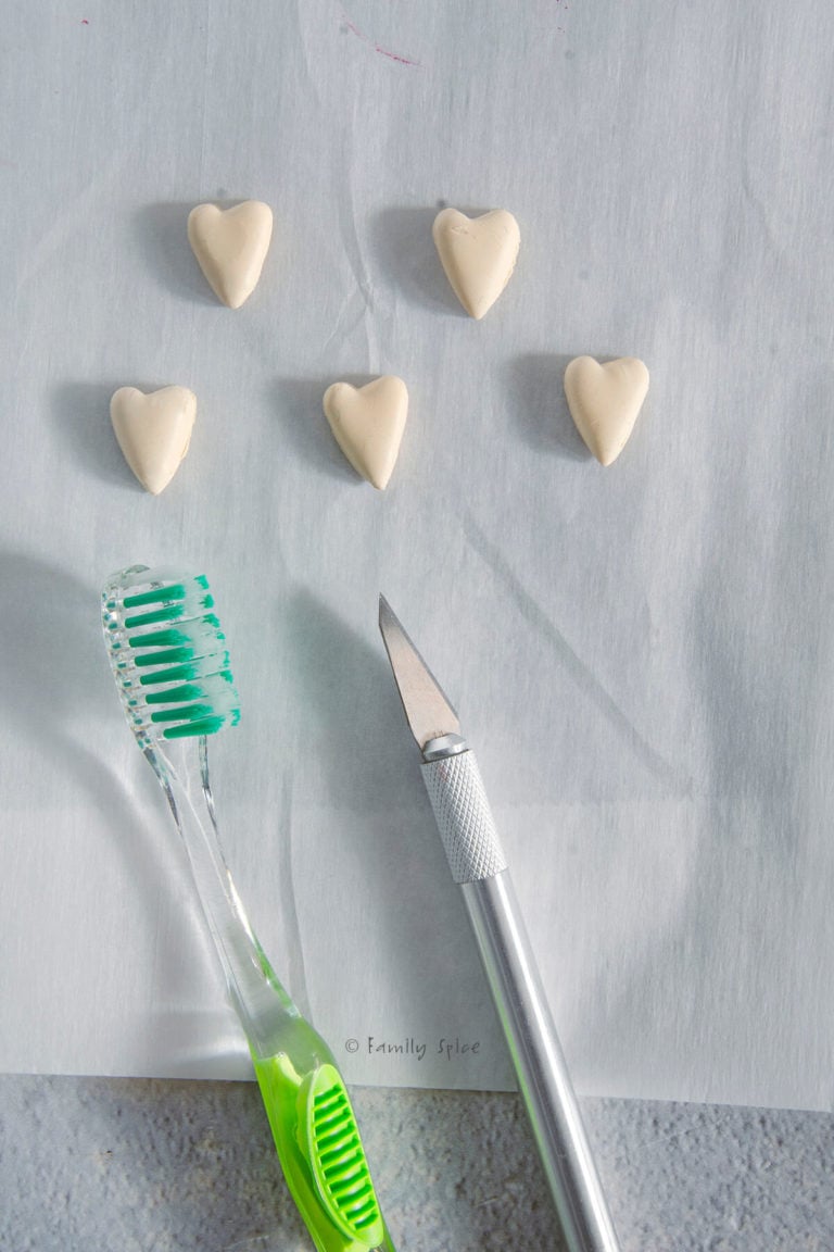 Texturing red polymer heart cookies with a toothbrush or xacto blade