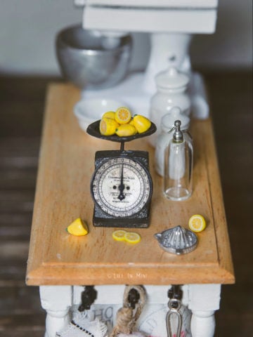 A miniature antique kitchen scale in a dollhouse kitchen table