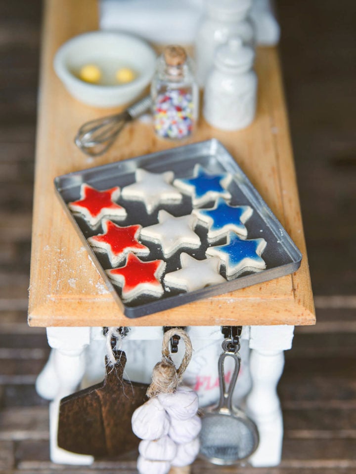 A large miniature baking sheet with star cookies on a dollhouse kitchen island