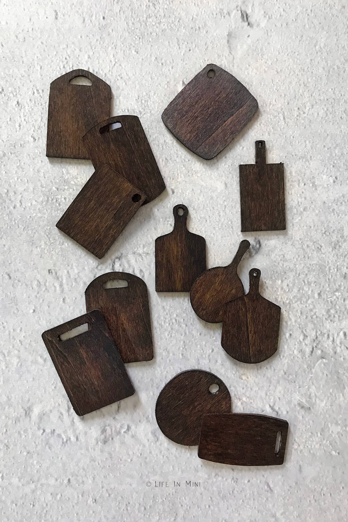 Miniature wood cutting boards of various shapes and sizes stained dark brown