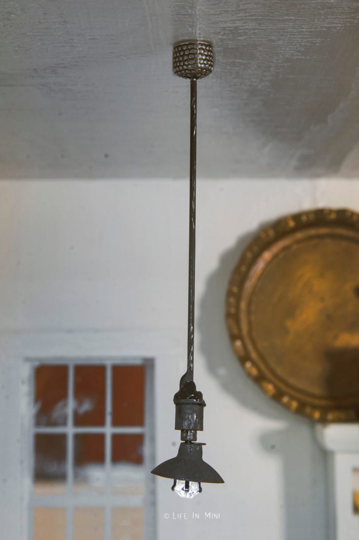 Closeup of a mini dollhouse pendant light hanging from the ceiling