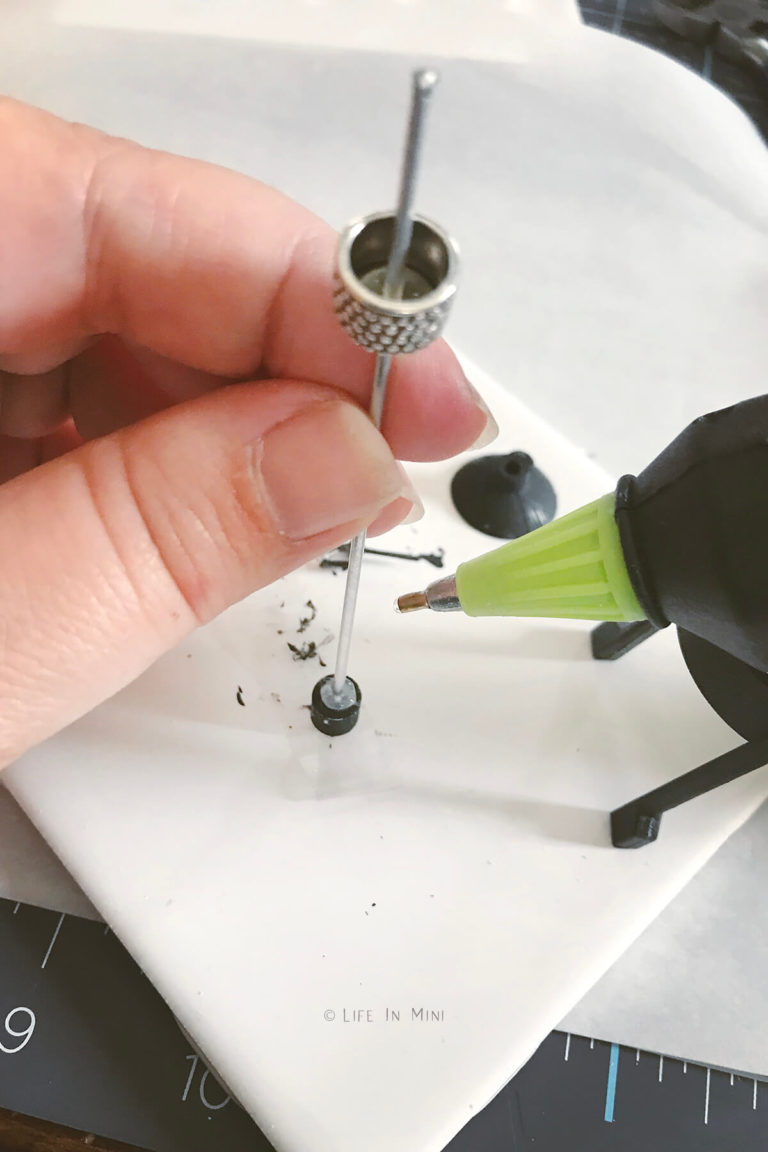 Hot glue gun adding hot glue to earring back with a bead at the other end