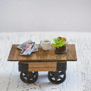 A miniature farmhouse coffee table with pulley wheels on a white background