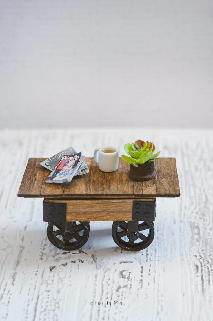 A miniature farmhouse coffee table with pulley wheels on a white background