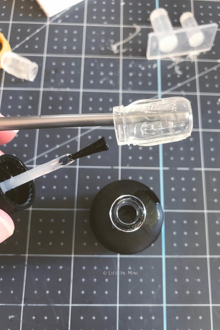 Brushing on clear UV nail polish onto a dollhouse mason jar