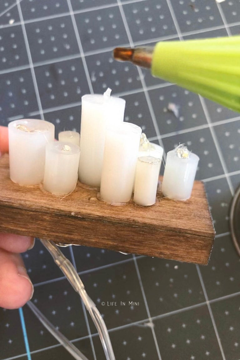 Adding hot glue to a miniature candle chandelier