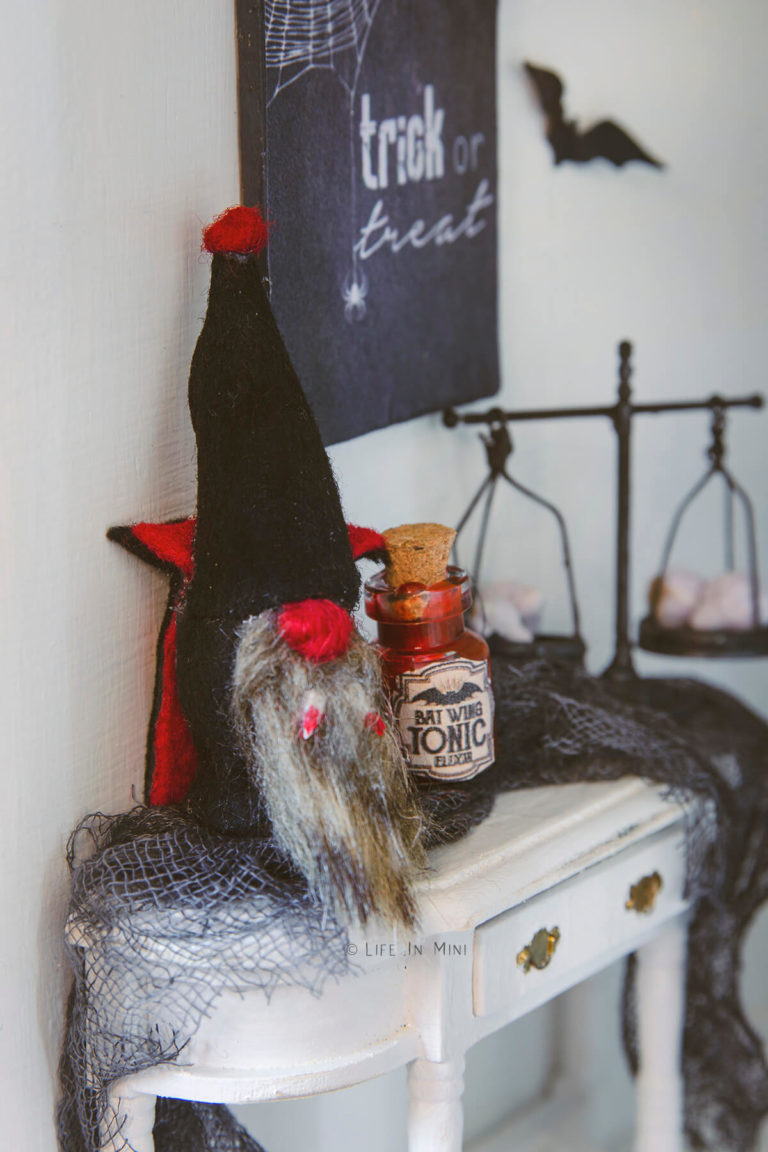 A miniature vampire gnome on a white table with other halloween decorations