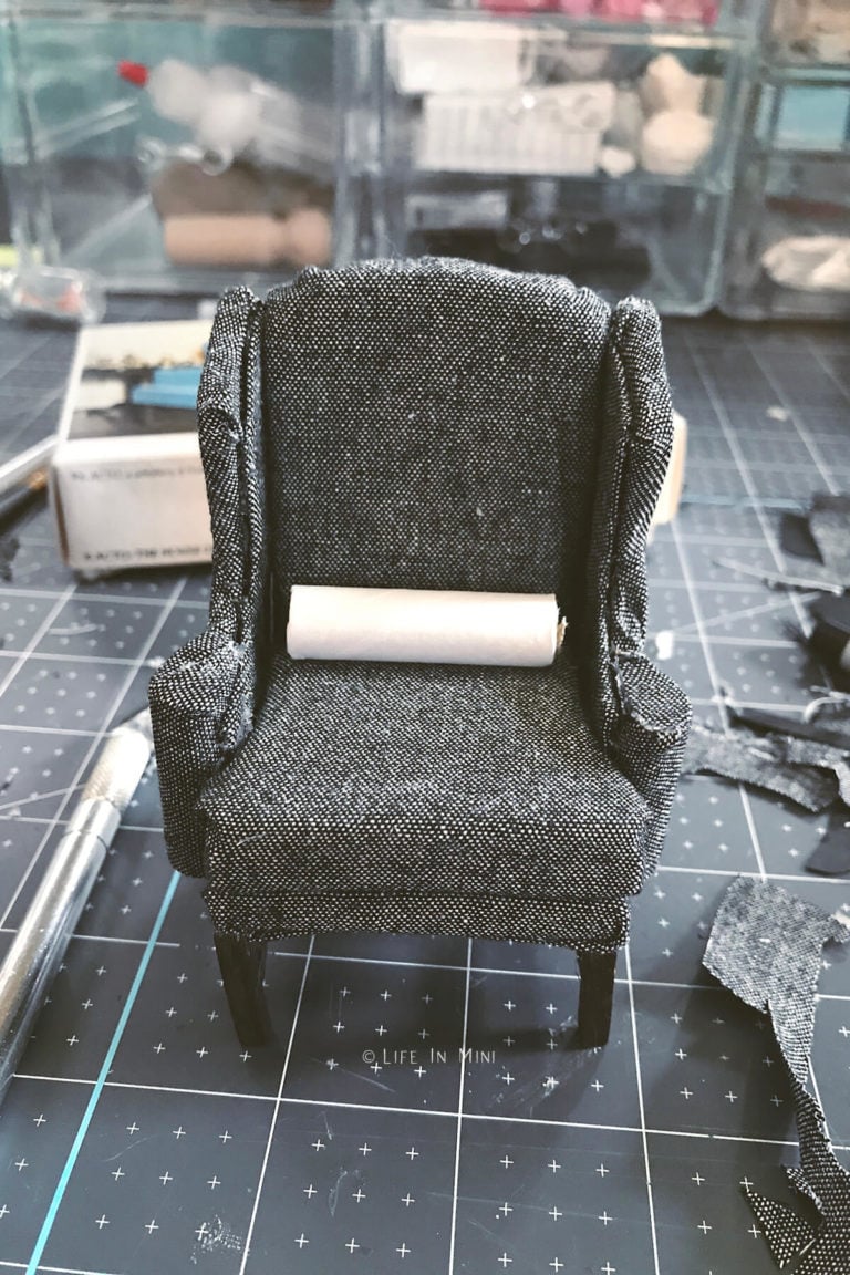 A small cardboard tube in a miniature wing chair