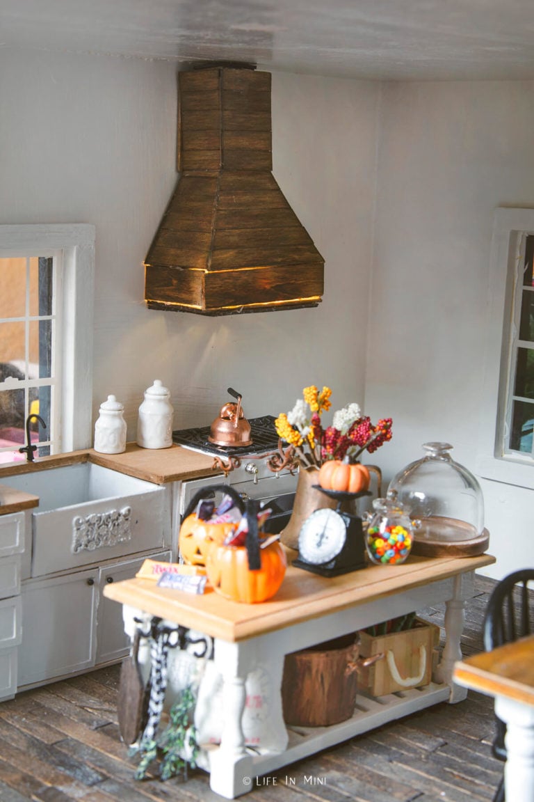 Dollhouse kitchen with halloween candies and pumpkin with a wood range hood behind it