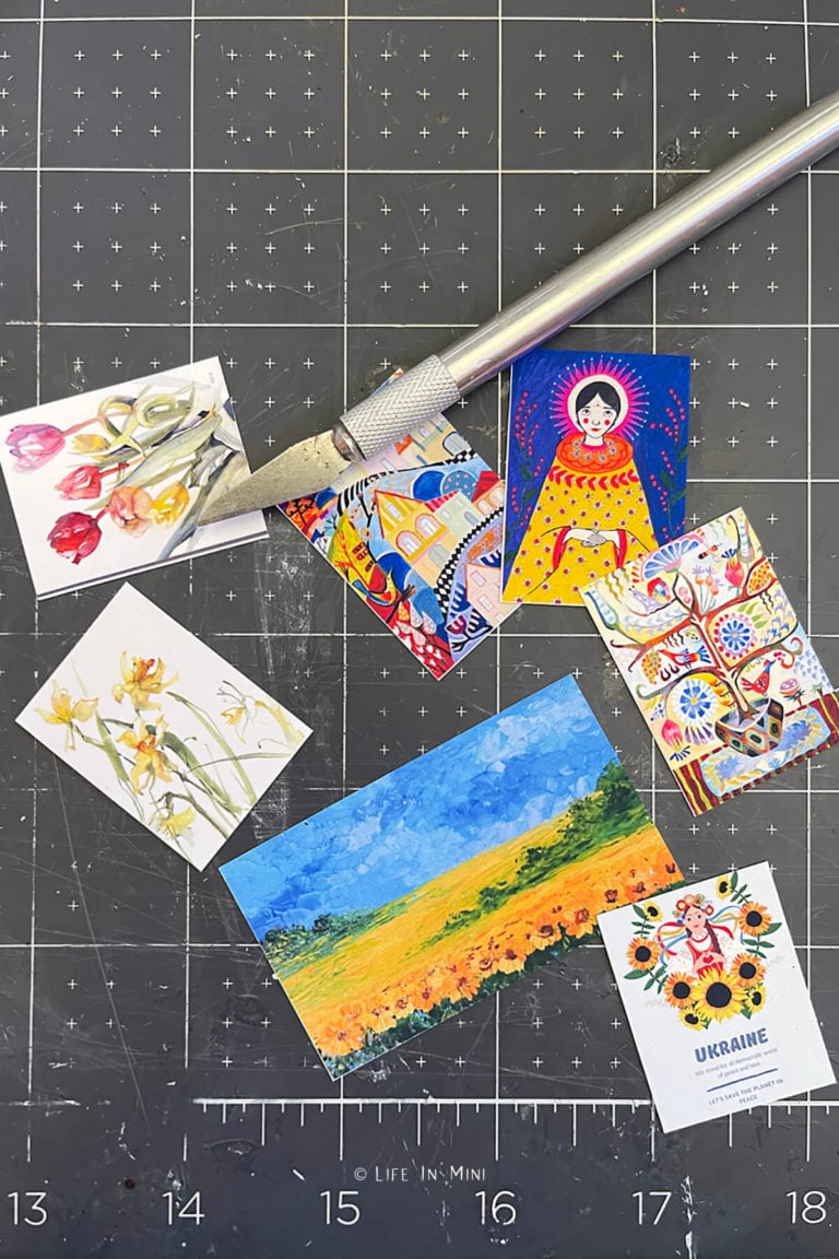 Various pieces of miniature artwork cut out with an xacto knife next to it