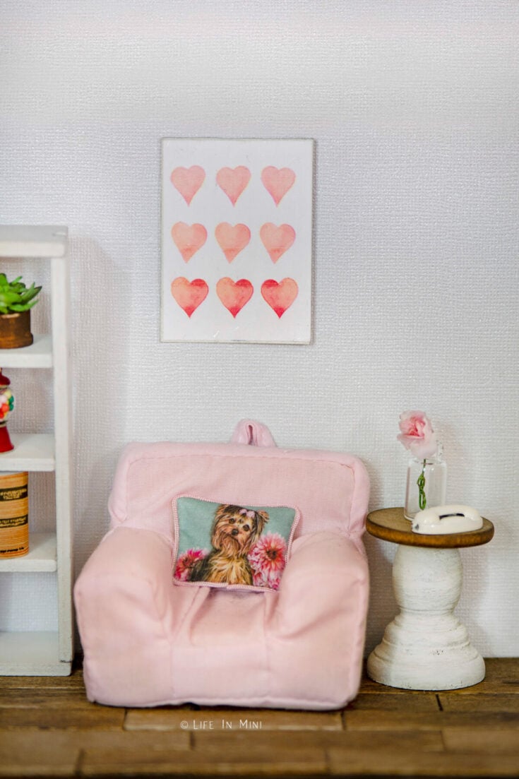 A small pink miniature chair with a small table in a dollhouse