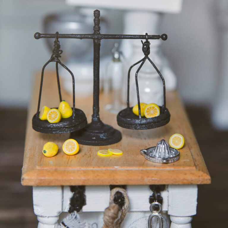 CLoseup of a miniature antique scale with lemons on it in a dollhouse kitchen