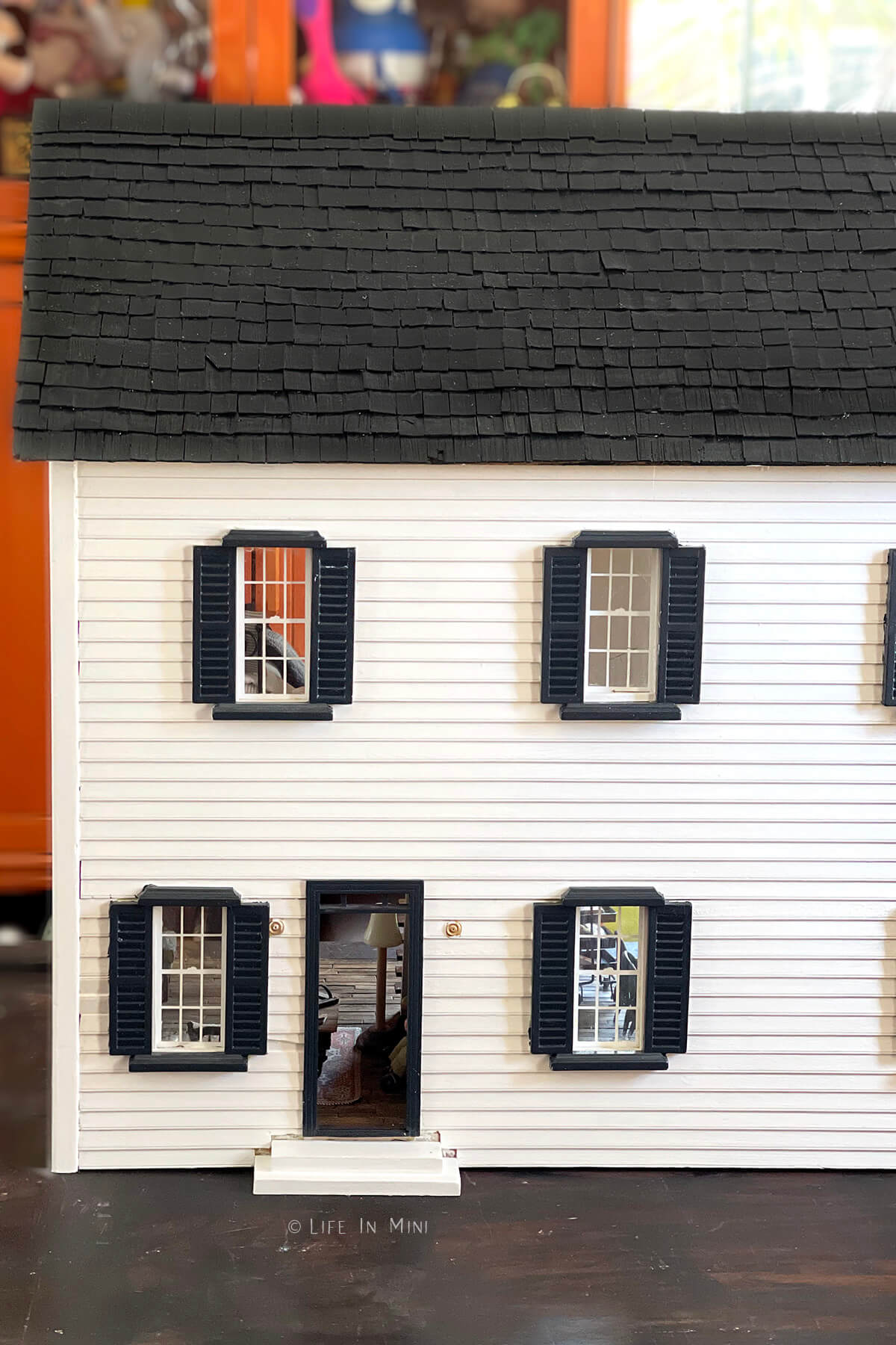 A white wood dollhouse with black trim and black roof