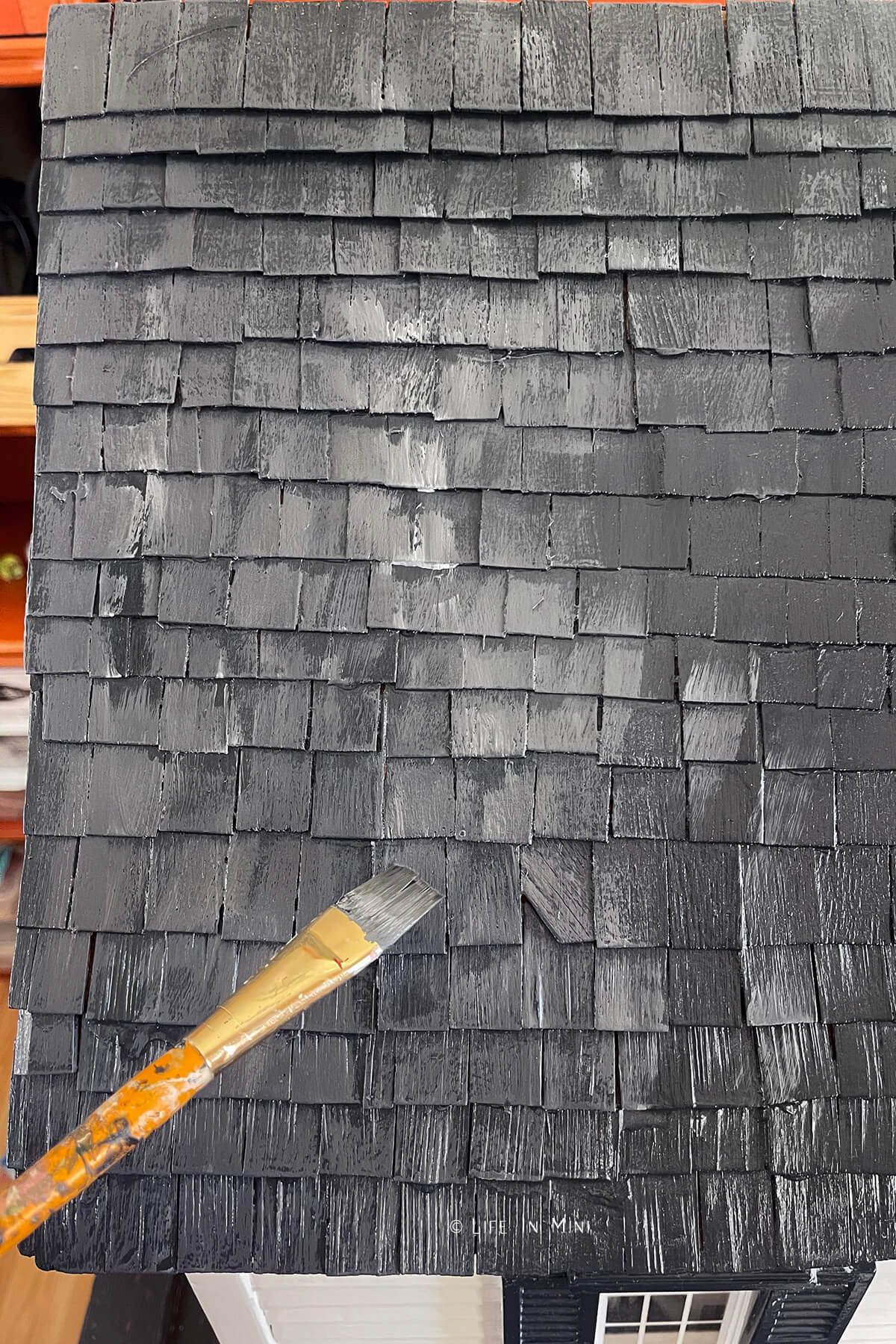 Closeup of a paint brush adding white highlights for a faux slate dollhouse roof