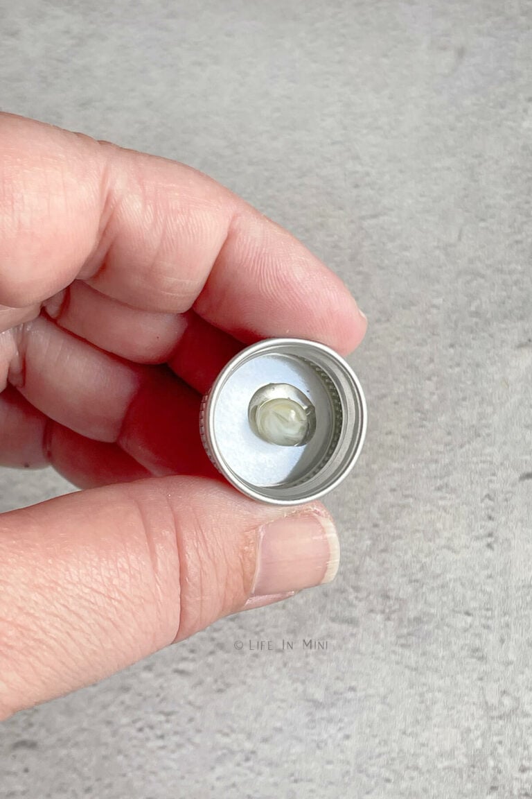 A mini metal jar lid with a spot of glue on it