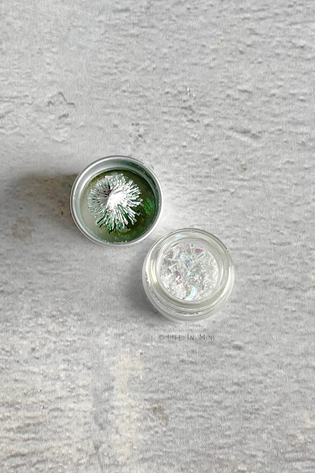 A mini glass jar with glitter and its lid with a mini tree glued on it