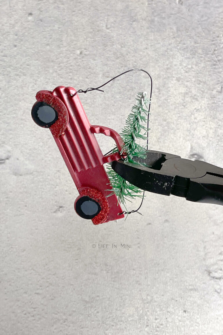 Using wire cutters to cut bottle brush tree from an ornament