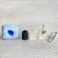 A homemade silicone mold with a tire cap, resin bottle, paper clip and miniature plant mister