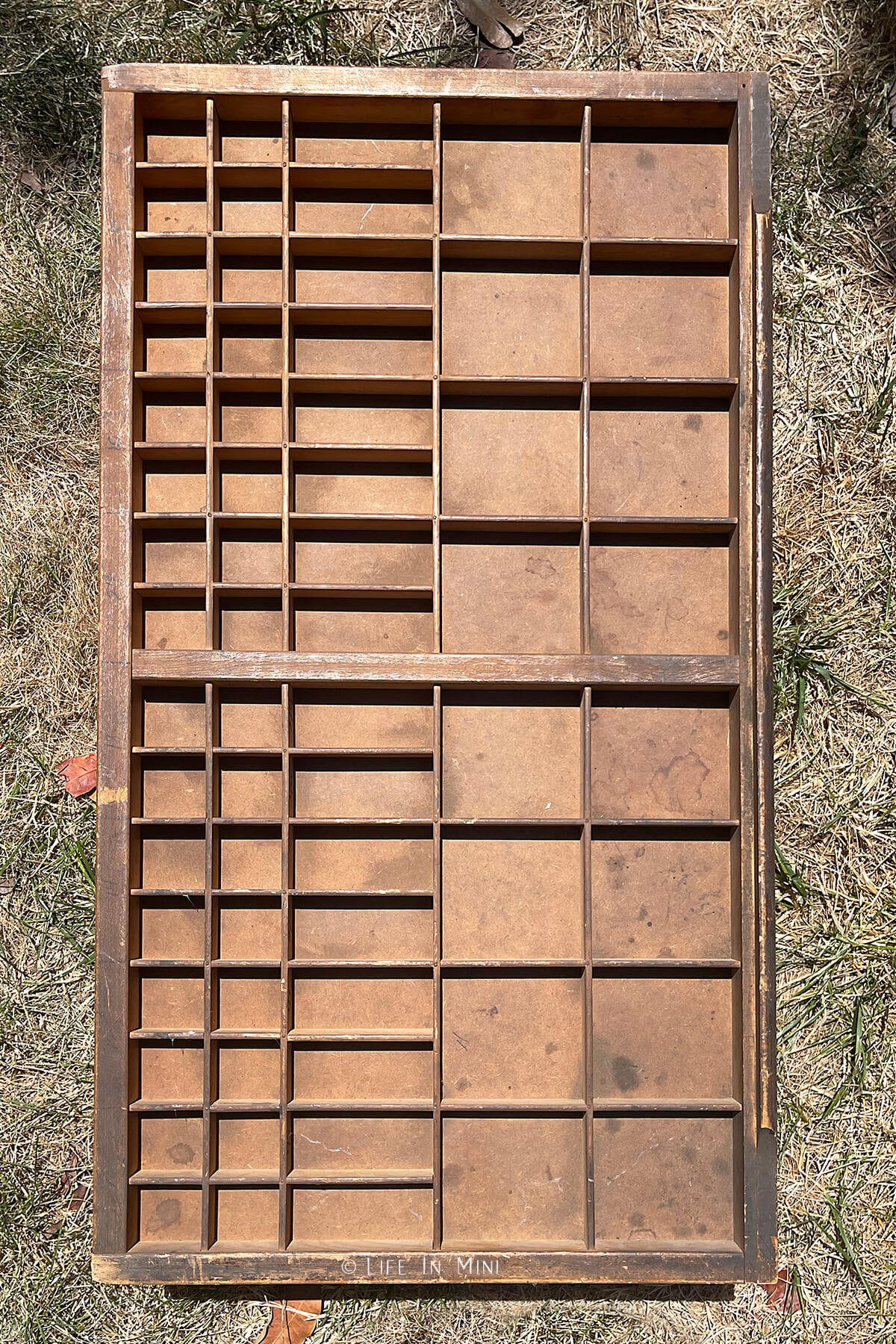 A vintage letterpress tray outside on the grass