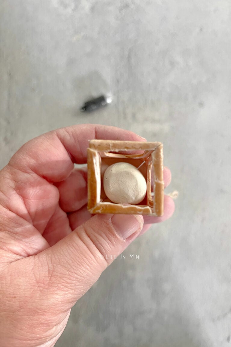 Looking into an open miniature lantern with air dry clay placed in it