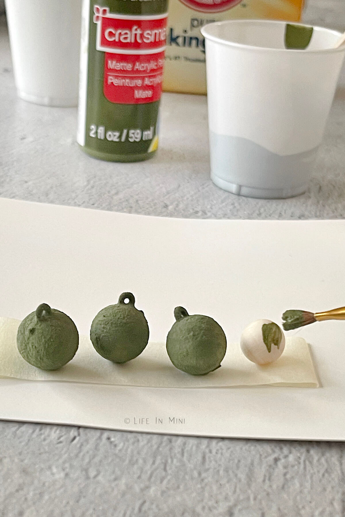 Miniature balls on masking tape getting painted with homemade green chalk paint