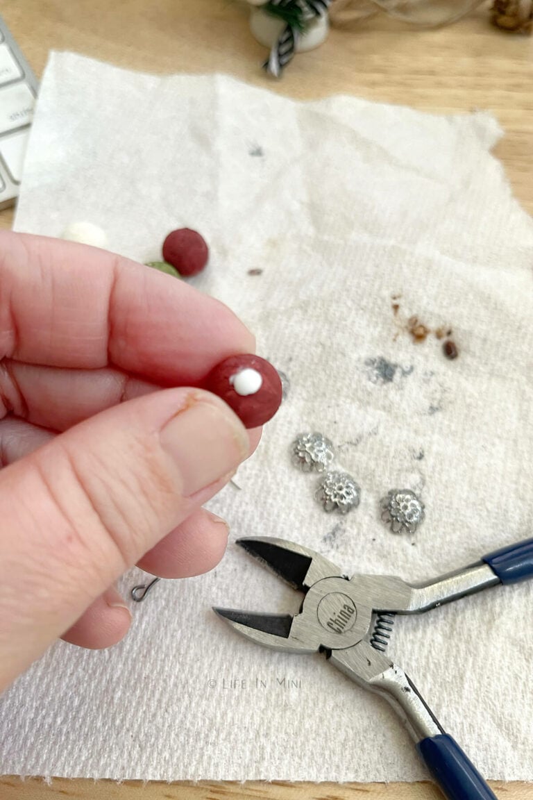 Adding a dab of white glue to a mini wooden ball painted brick red