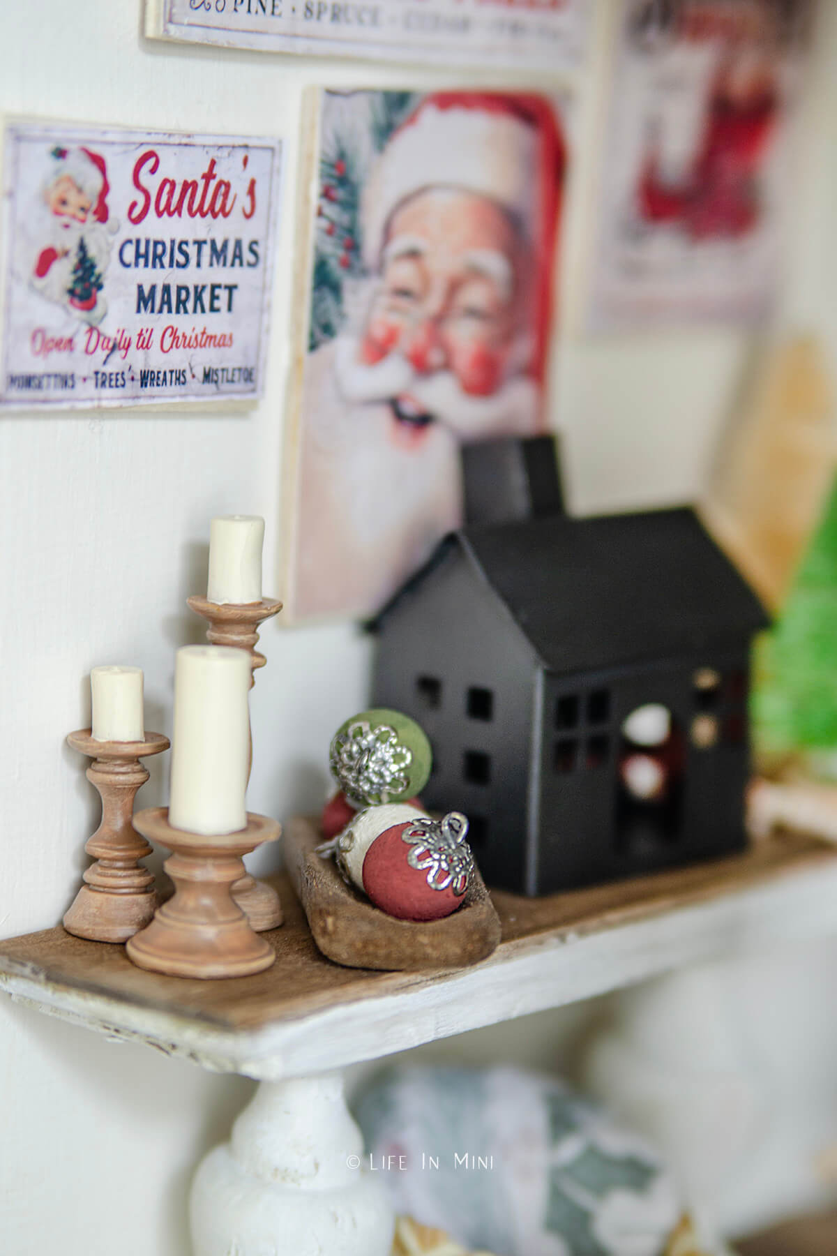 A dollhouse console table with various holiday decor items on it with a wood tray with homemade chalk painted ornament balls in them