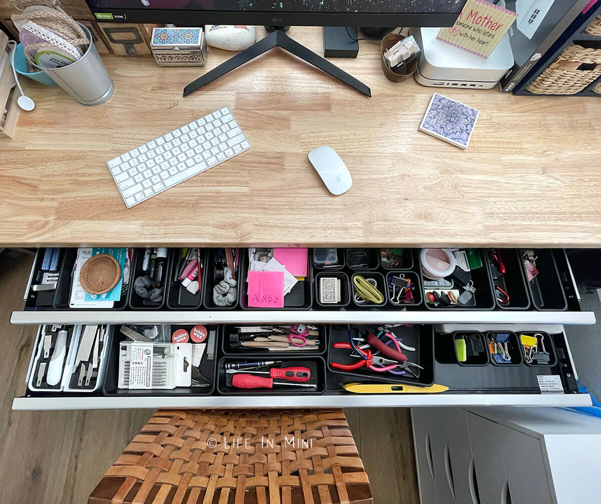 Closeup of the inside of two drawers in a work table being used as a desk and craft table