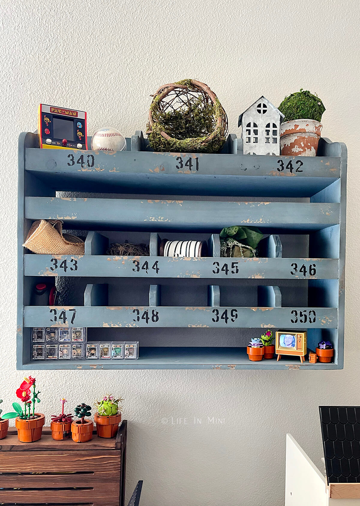A blue antique shelf unit hanging on the wall with various items in it