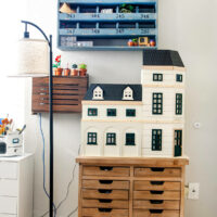 Closeup of a craft room organized with vintage pieces and a dollhouse
