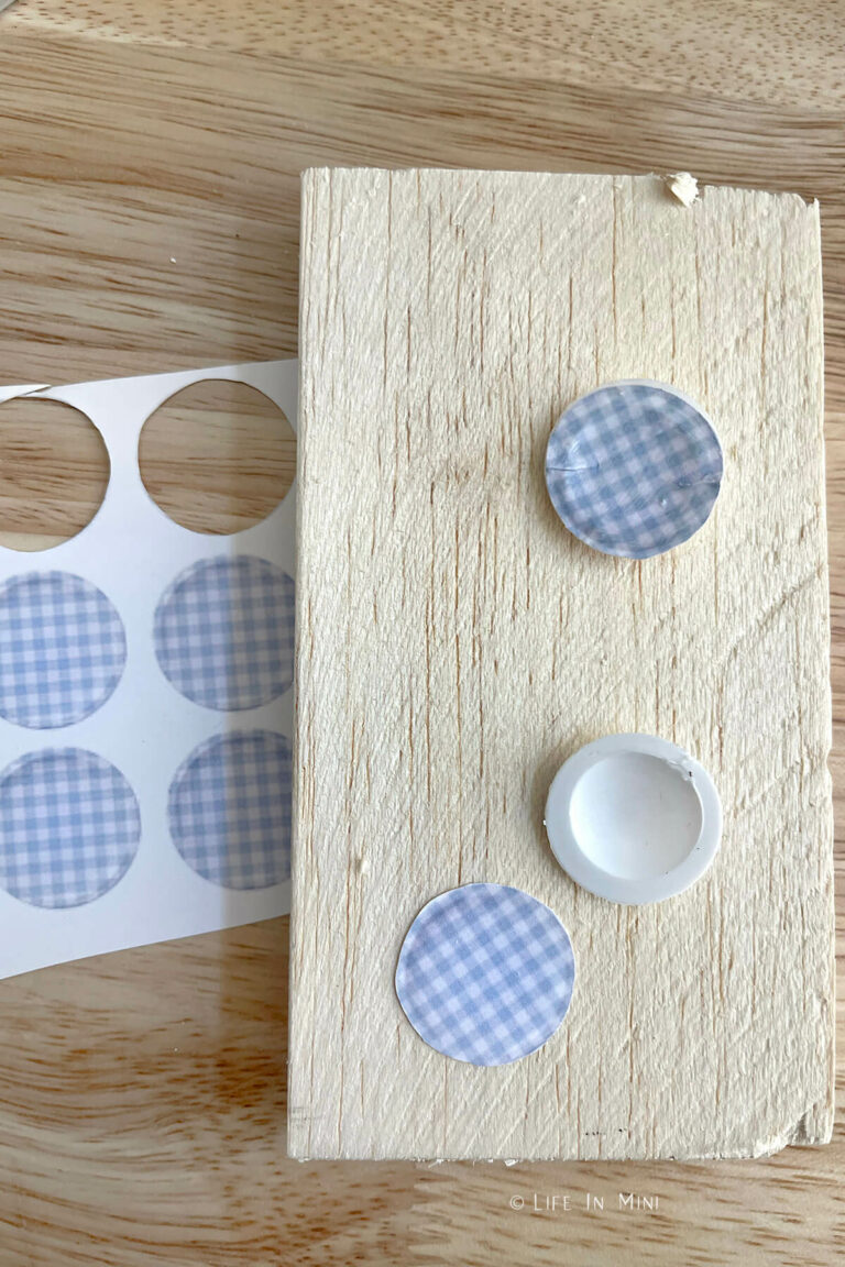 Small blue paper rounds cut out and a plastic disc on a block of balsa wood