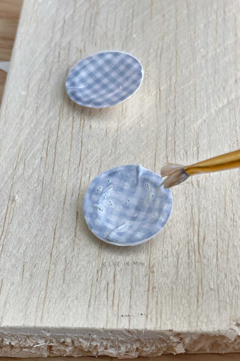 Adding Mod Podge with a brush to miniature blue plates