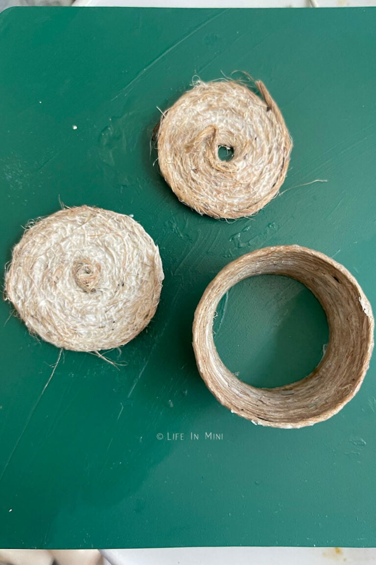 A twine bottom, basket form and lid waiting on a work surface for the glue to dry