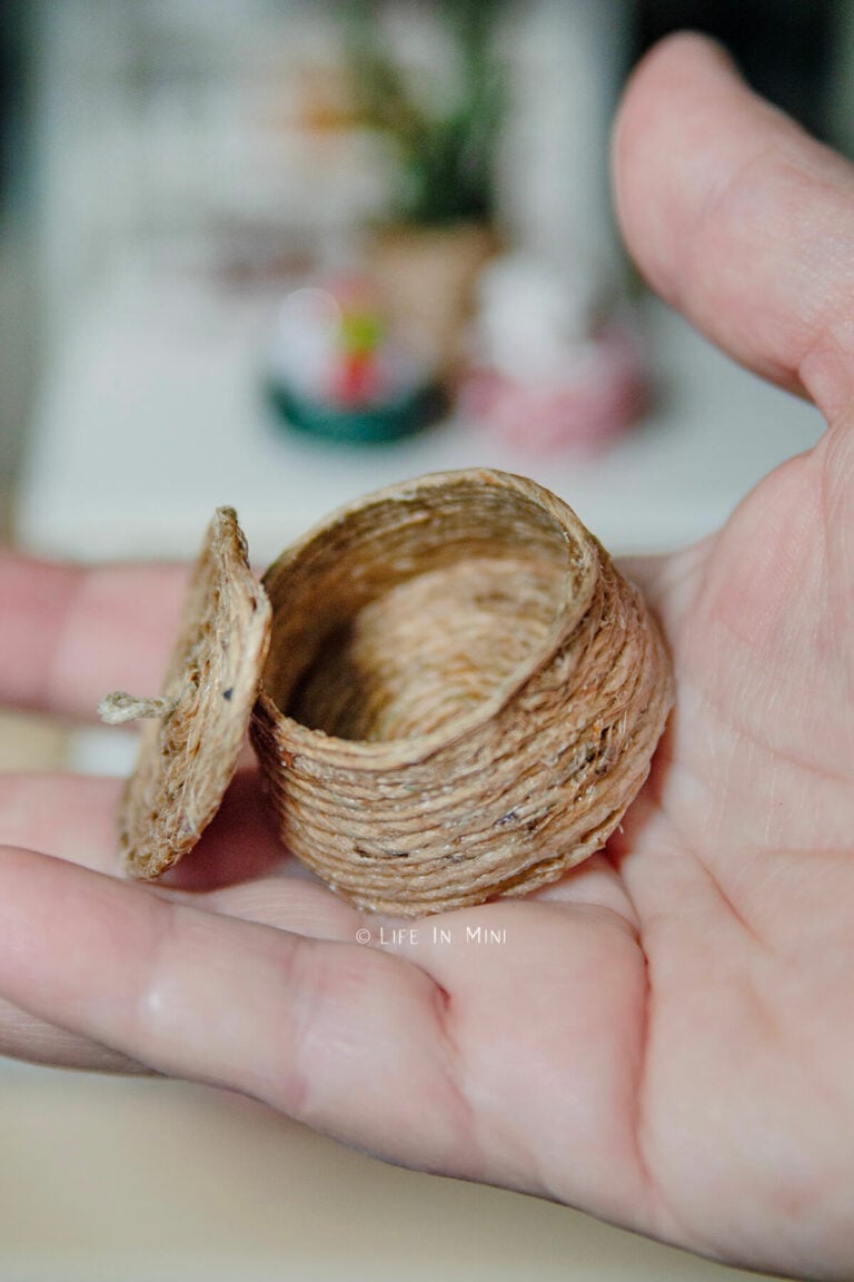 A hand holding a mini basket made with twine with a lid