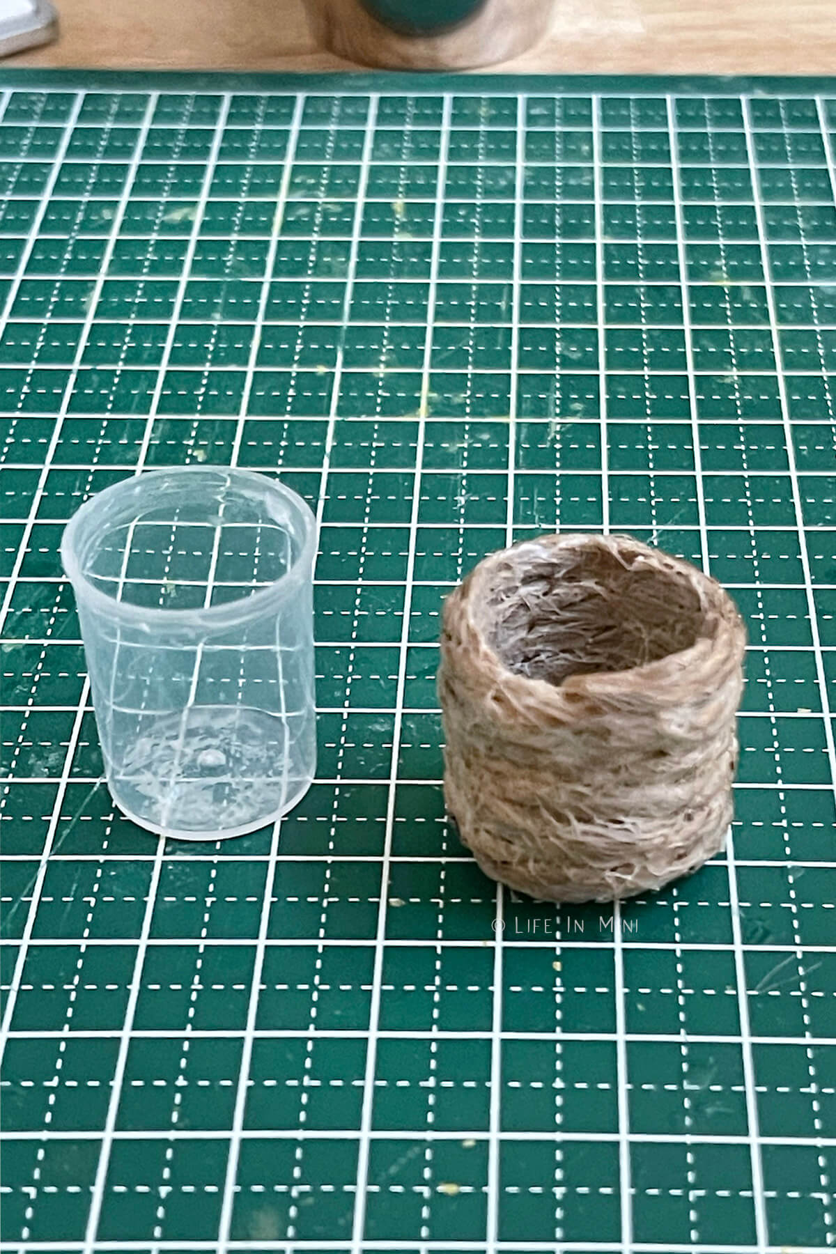 A small plastic cap with a mini basket made from twine and glue next to it