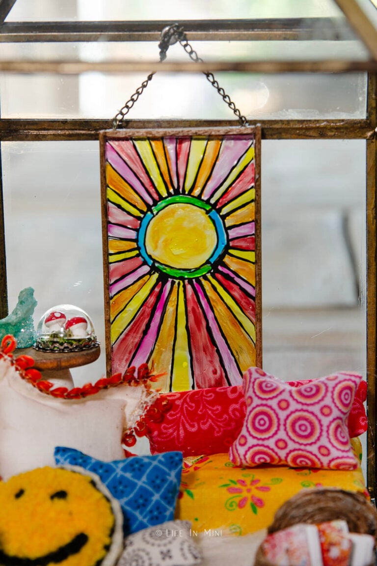 Closeup of a miniature sun design stained glass inside a boho reading nook scene made in a lantern.