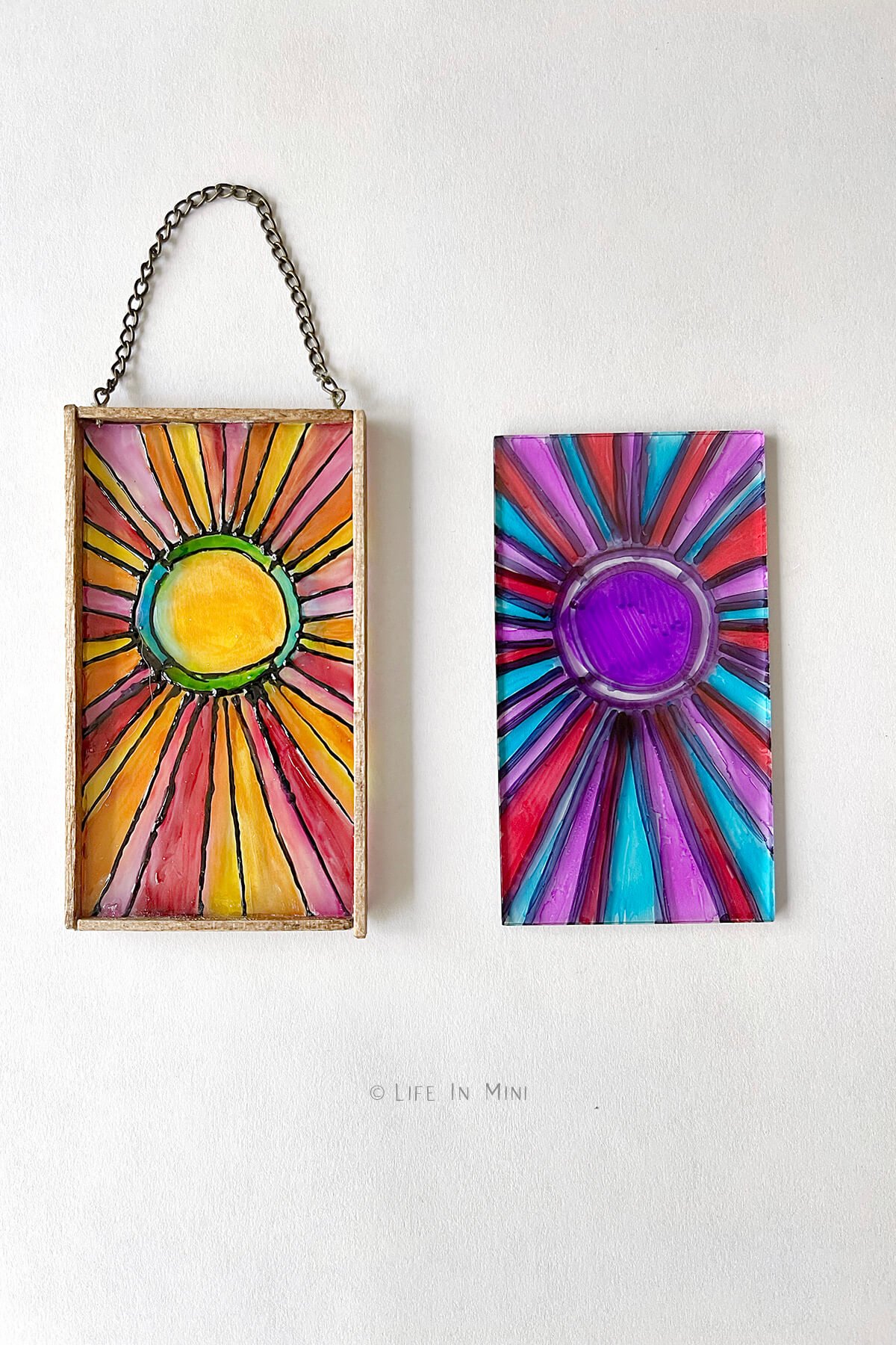 A miniature sun design stained glass made with glass paint next to the same design but colored with permanent marker