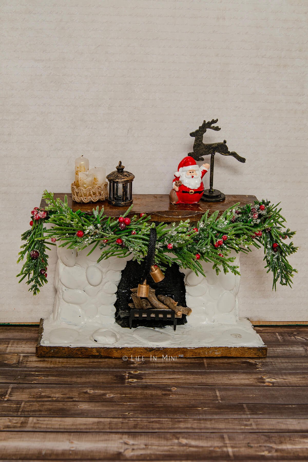 A dollhouse fireplace mantle decorated for Christmas.