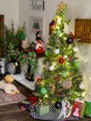 A miniature christmas tree decorated with ornaments in a dollhouse.