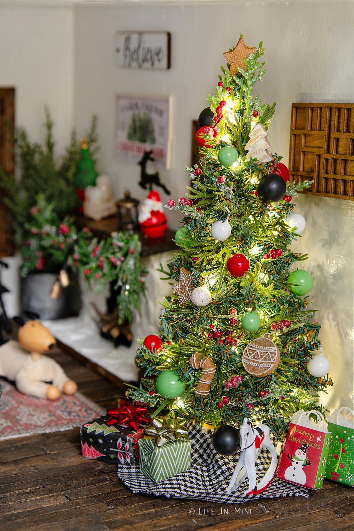 A miniature christmas tree decorated with ornaments in a dollhouse.