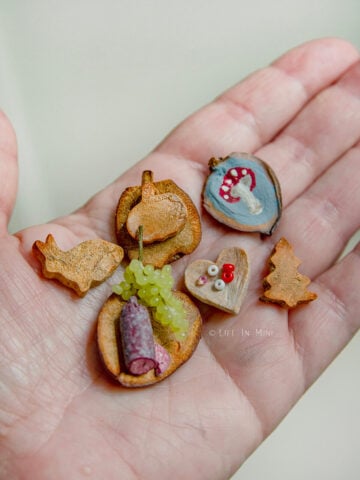 A hand holding a variety of cutting boards in different shapes made from avocado pits.
